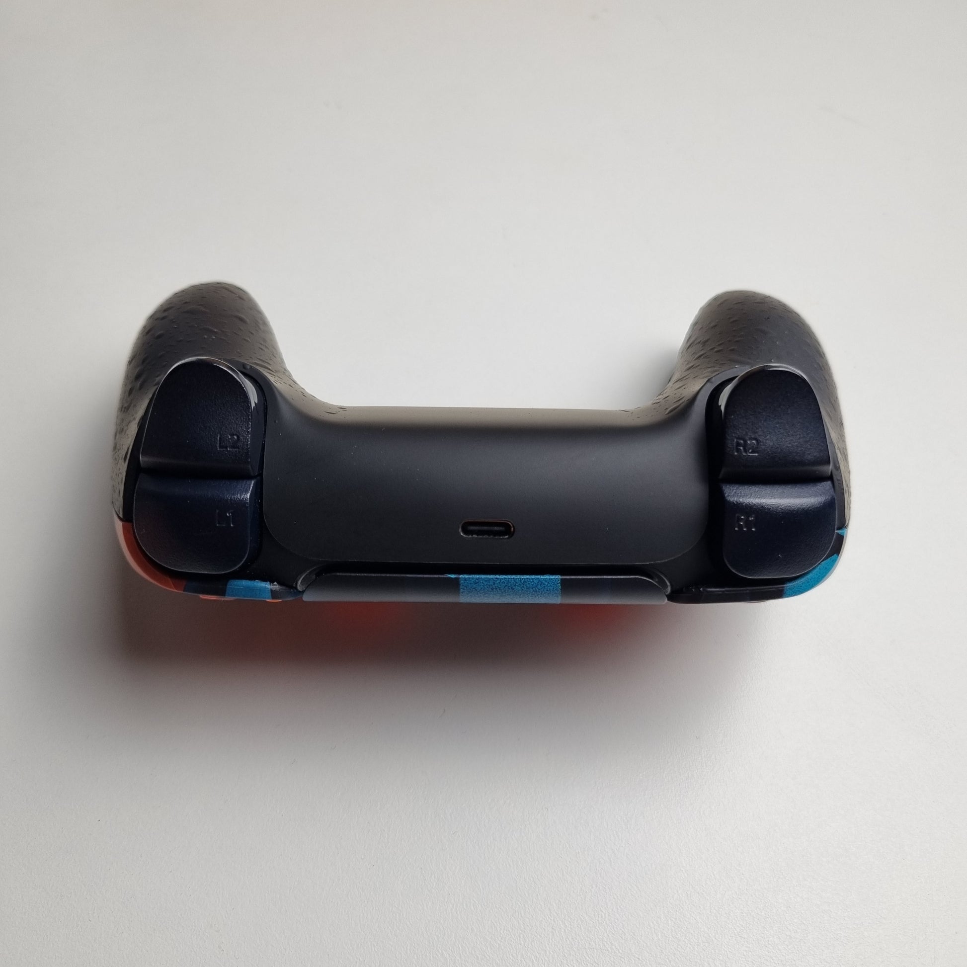 Black top of a custom PS5 controller built by Dogghead Tech on a white background.