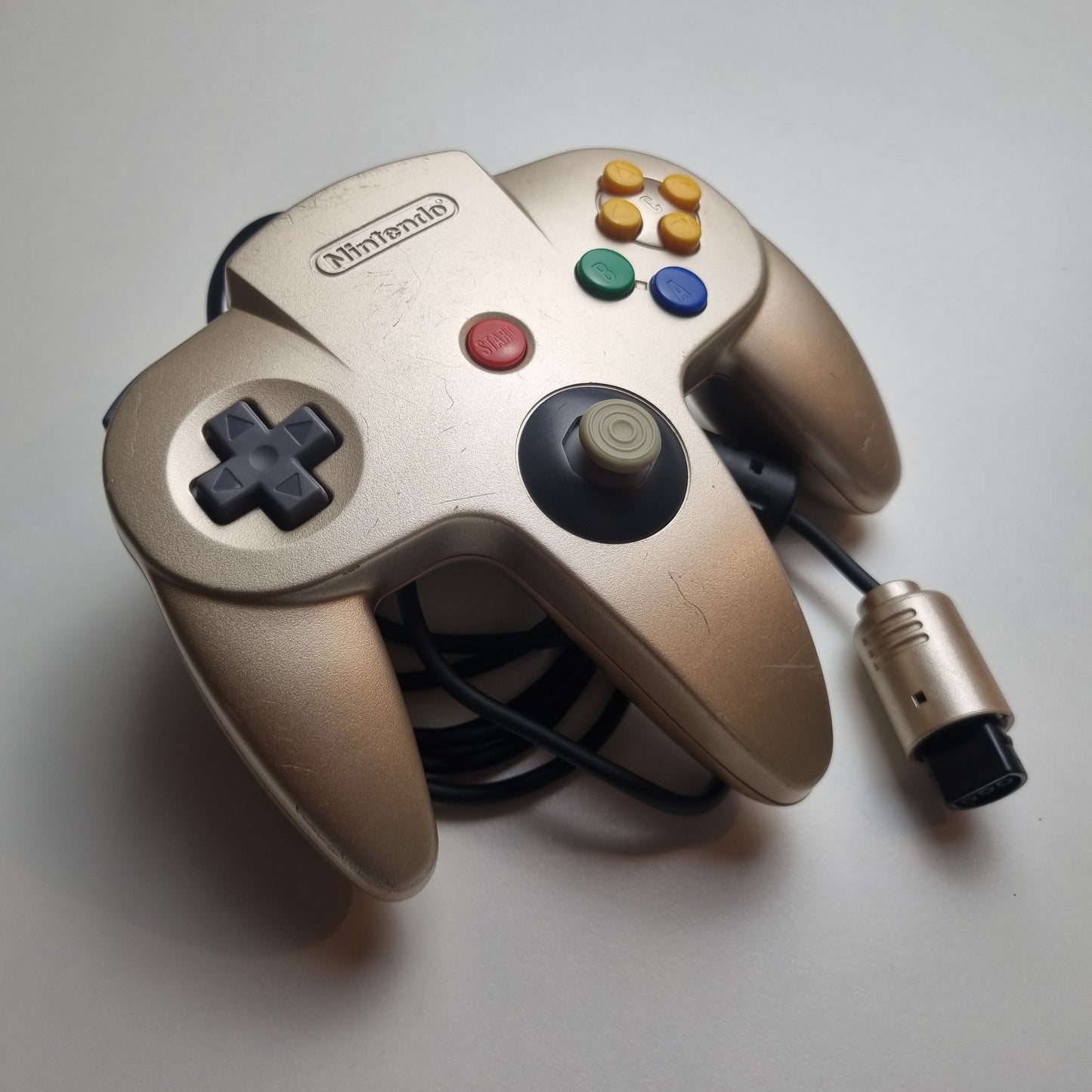 Refurbished modified gold Nintendo 64 controller on a light grey background.