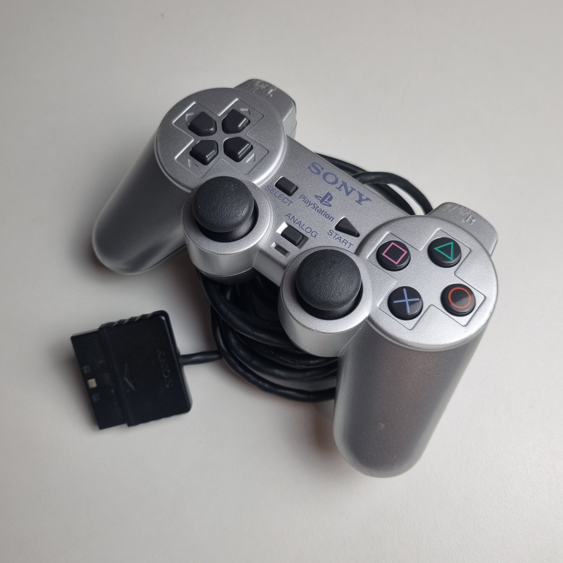 Refurbished official silver Sony PlayStation 2 wired controller, showing signs of wear and tear.