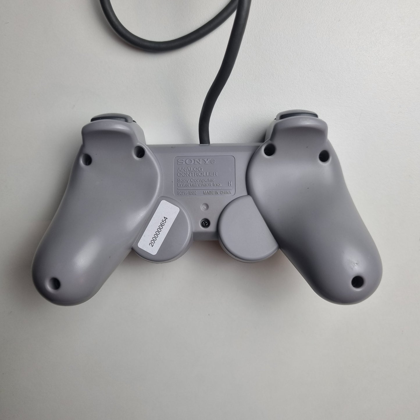 Back of a refurbished official Sony PlayStation DualShock wired grey controller, on a white background.