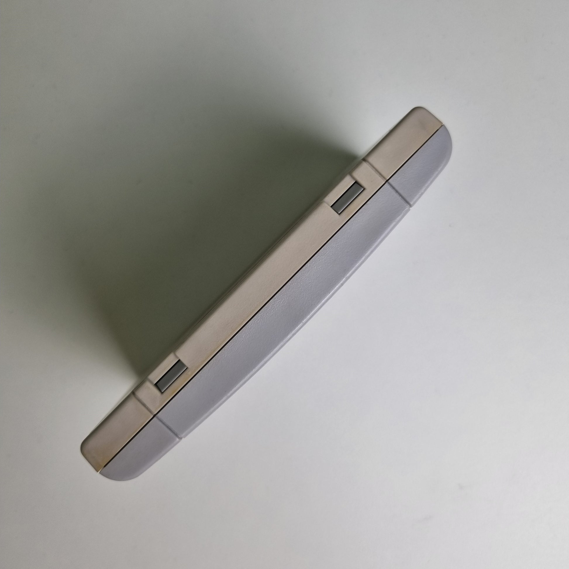 Top view of a Super Nintendo game cartridge showing discolouration between the two sides, on a light grey background