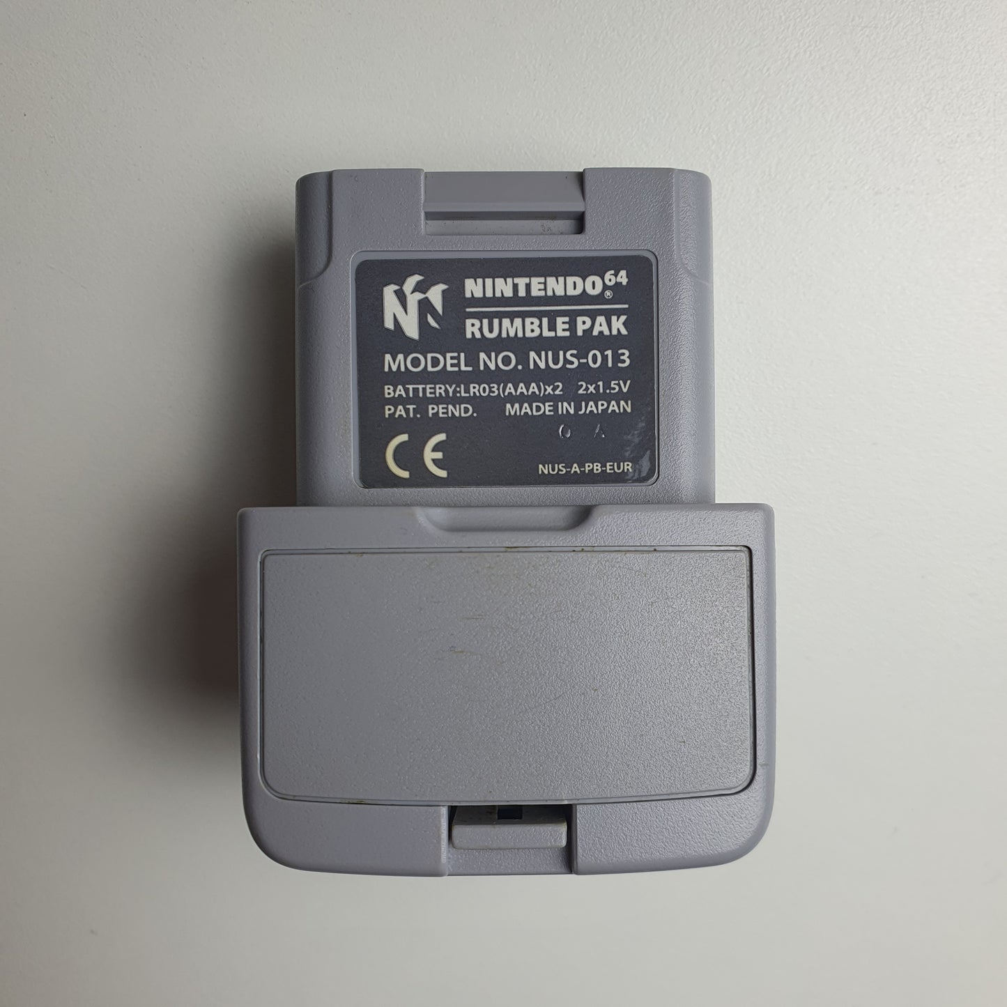 Grey Nintendo 64 N64 rumble pak on a white background 