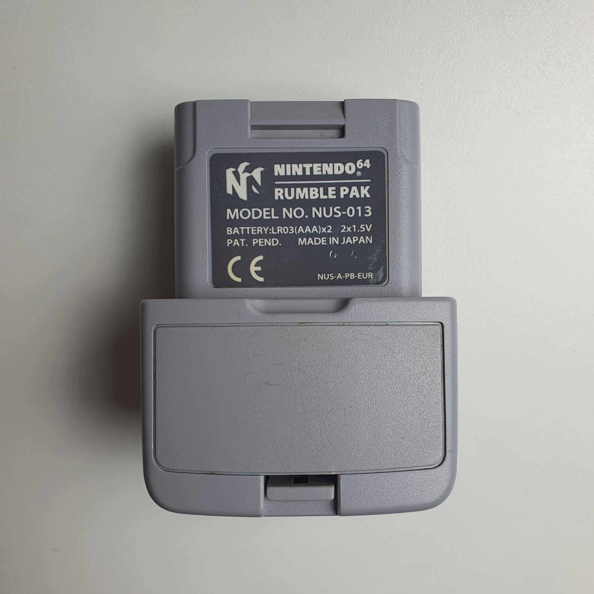 Grey Nintendo 64 N64 rumble pak on a white background 