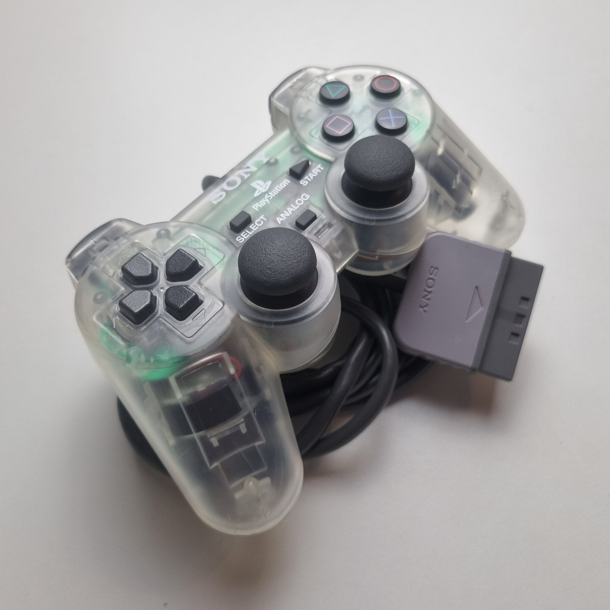 Clear official Sony PlayStation 1 refurbished gaming controller with buttons on a white background