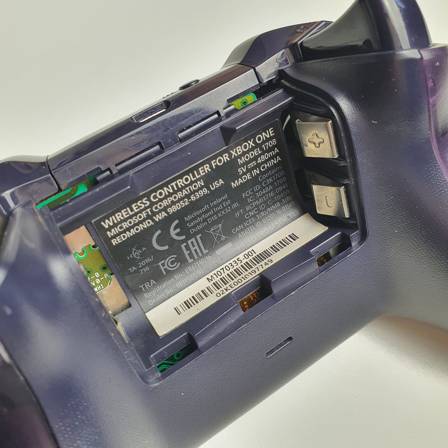 Close-up of a Xbox One controller with battery compartment open on a light grey background