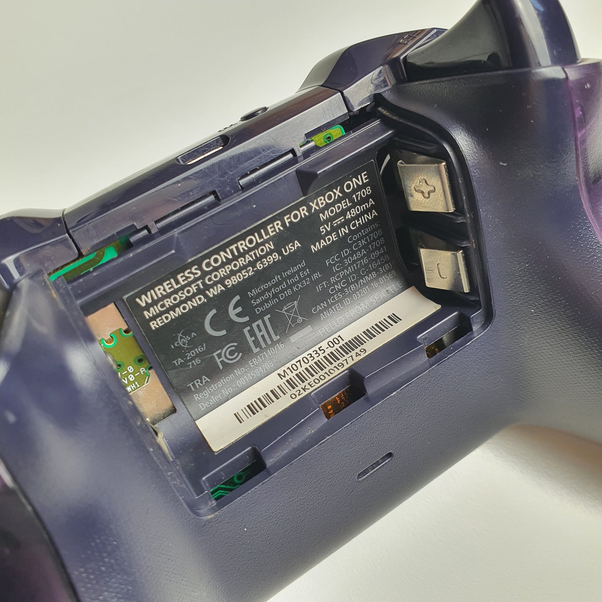 Close-up of a Xbox One controller with battery compartment open on a light grey background