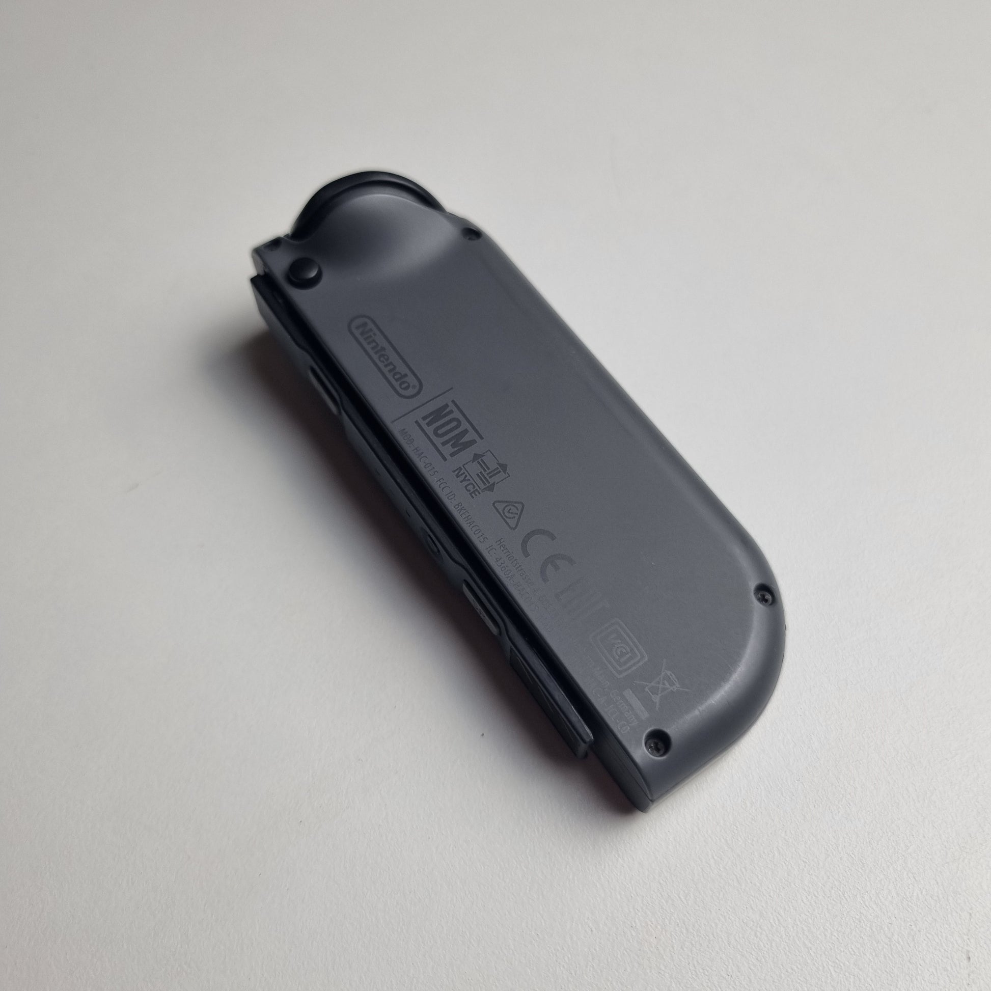 The back of a grey Nintendo Switch Joy-Con on a white background.