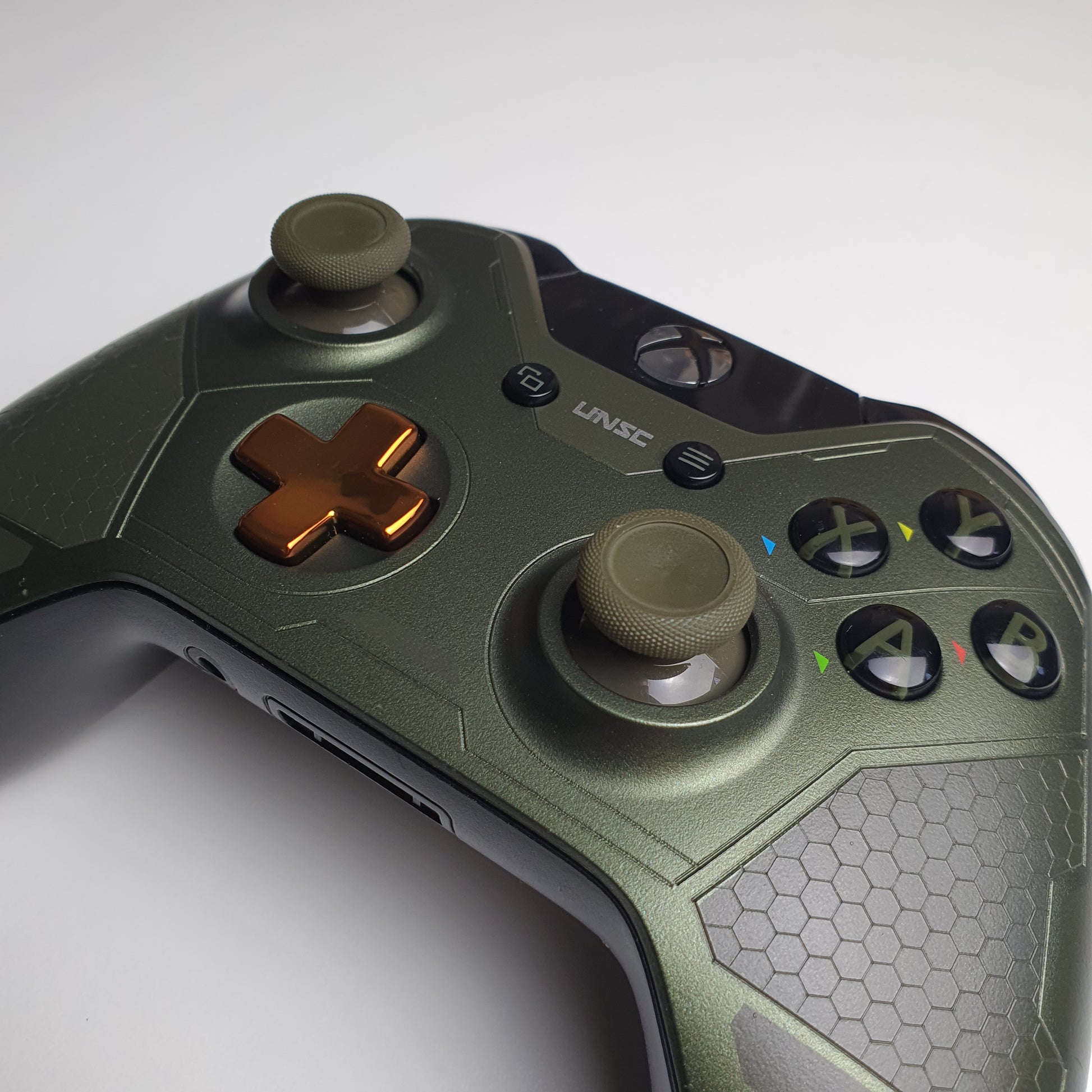 Close-up of a green & copper coloured Xbox One 'Master Chief' controller on a white background