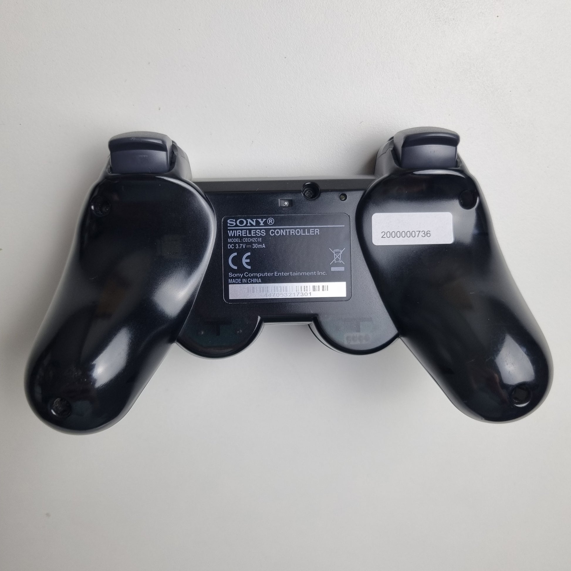 Back of a official Sony PlayStation PS3 SIXAXIS black wireless controller on a white background.