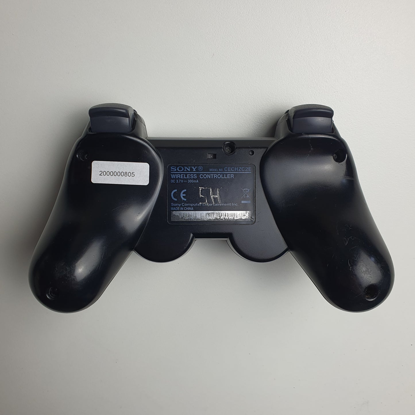 Back of a black PlayStation 3 controller on a white background