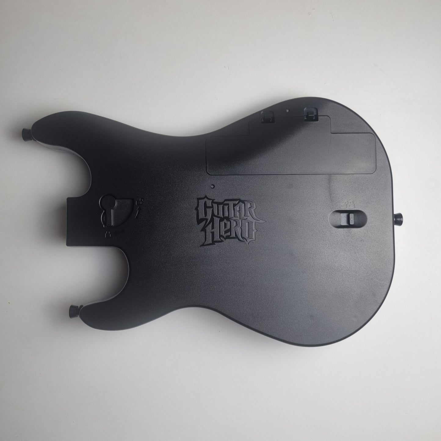 Back of a black guitar controller with 'Guitar Hero' branding on a white background