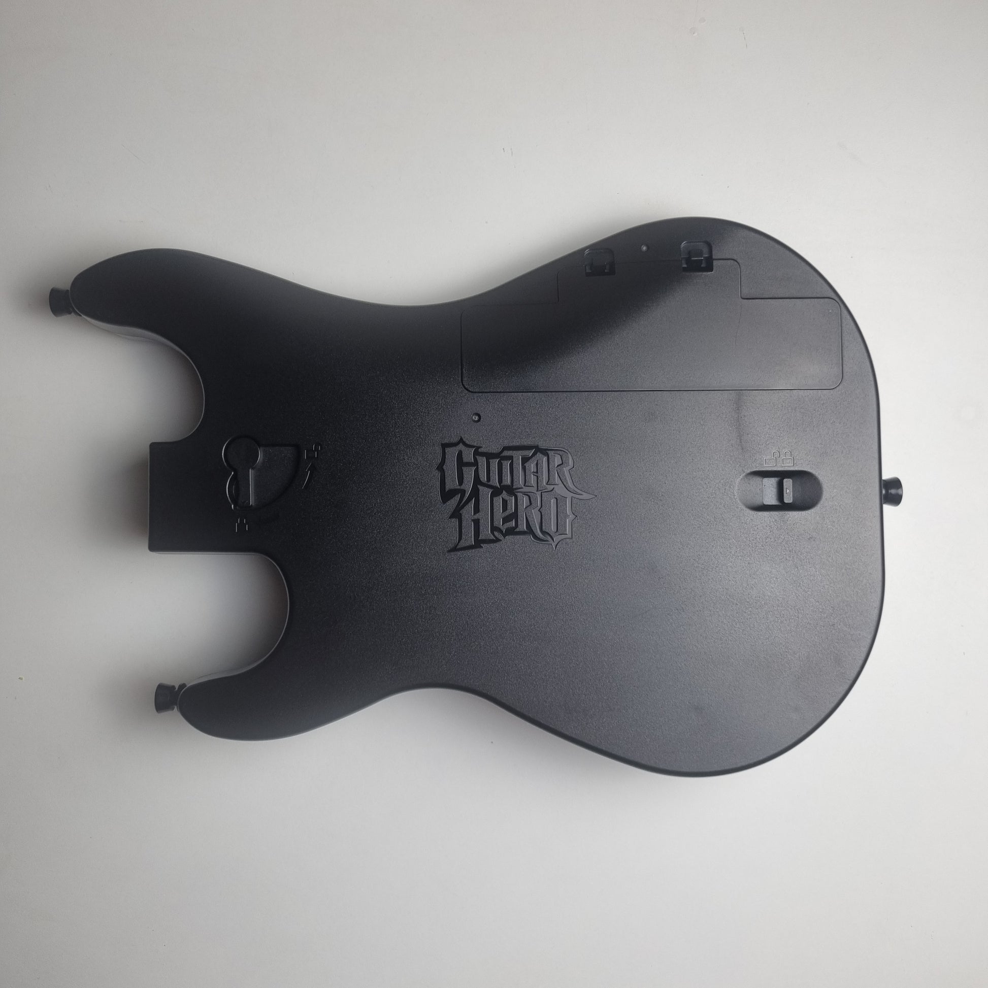 Back of a black guitar controller with 'Guitar Hero' branding on a white background