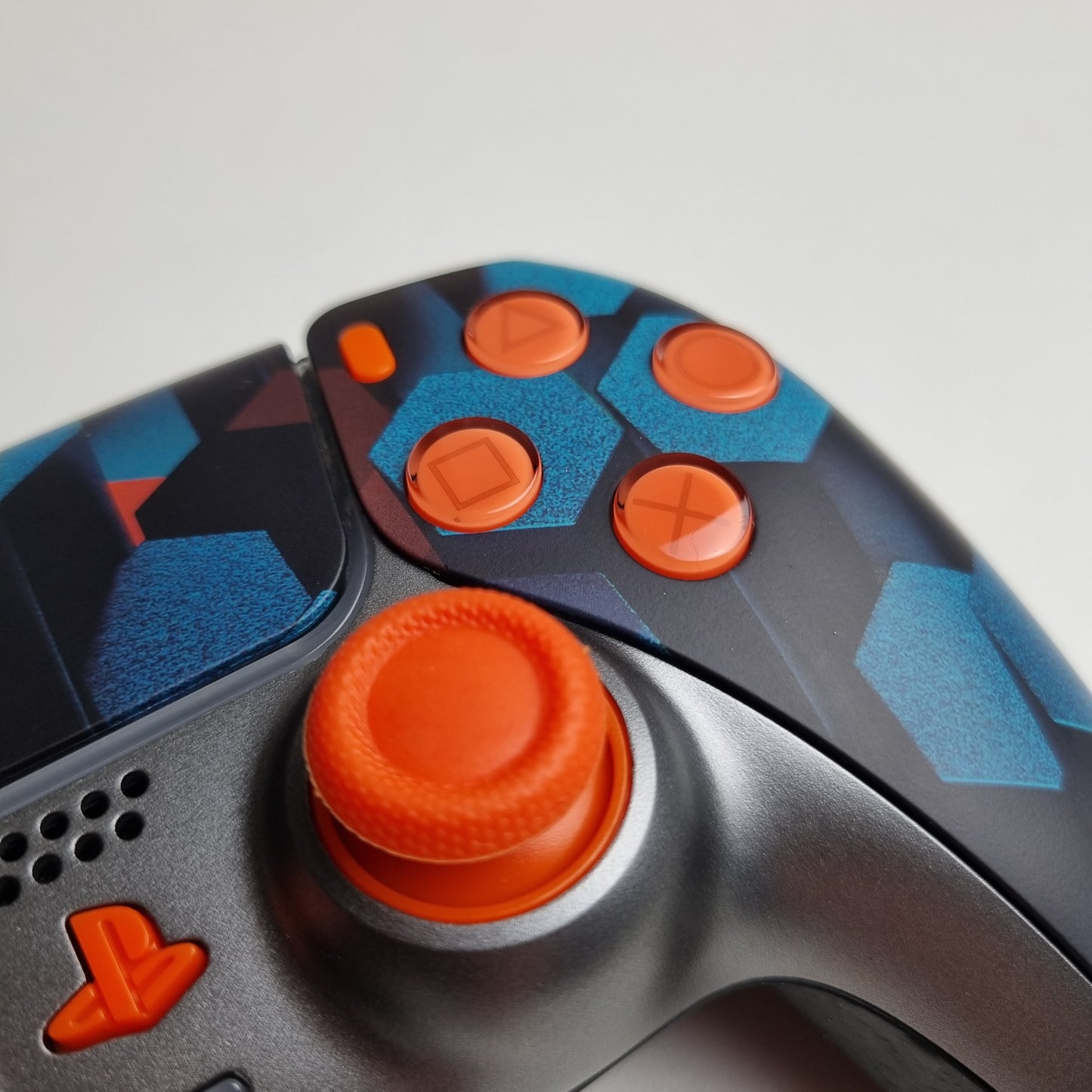 Close-up of the analog stick of a custom orange, teal & black Sony PlayStation 5 PS5 wireless DualSense controller built by Dogghead Tech on a white background.