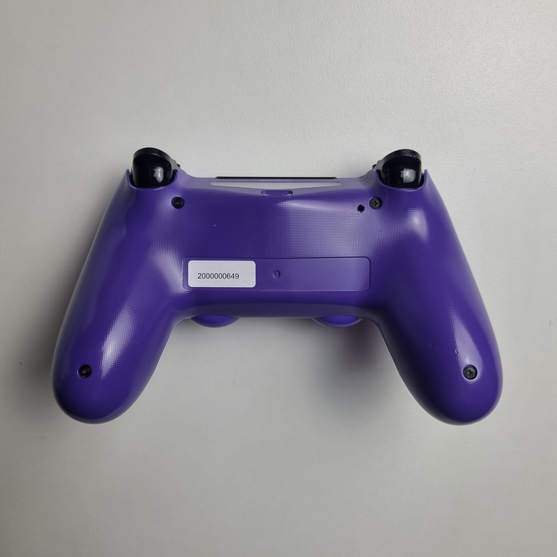 Back of an electric purple official Sony PlayStation DualShock 4 refurbished gaming controller on a light gray background