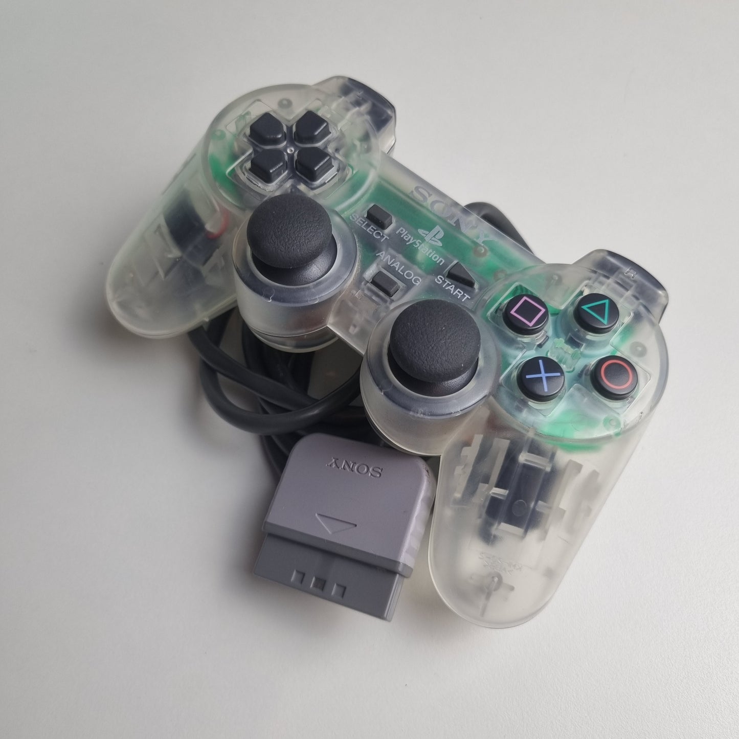Clear official Sony PlayStation 1 refurbished gaming controller with buttons on a white background