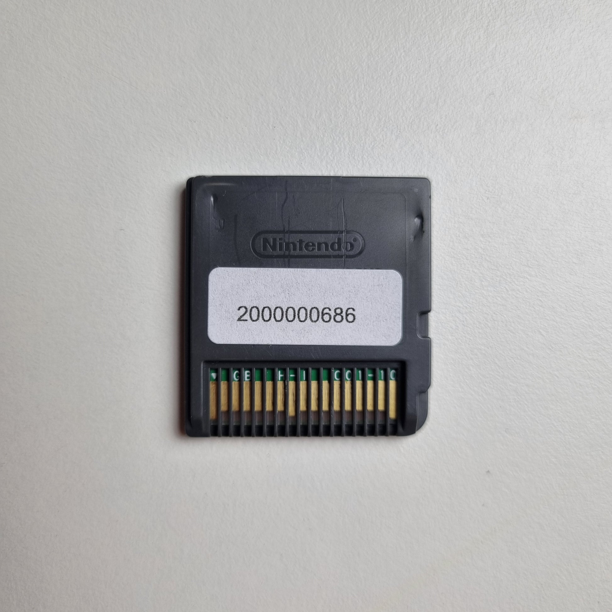 Back of a Nintendo DS game cartridge showing an asset tag, on a light grey background